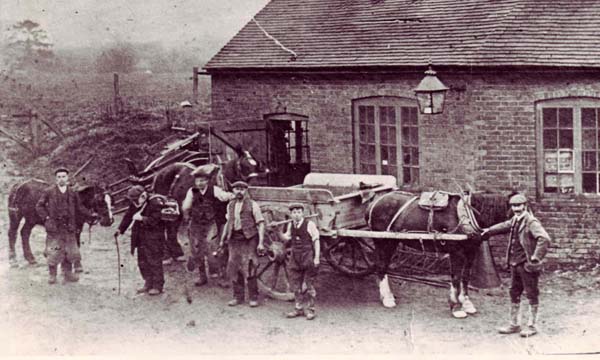 The Forge c 1909. Master blacksmith Jim Hobbs (fourth from left) is flanked by his sons Donald and Harold. Employee Walter Lambert holds the pony (extreme left) and the little old man, Jimmie Lock, retired and blind, carries a traveling blacksmith’s traveling toolbox. .