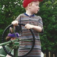 Boy at steering wheel of farm vehicle.