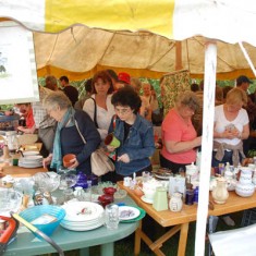 Crowded bric a brac stall. On the left, Hazel Rendle, one of the village residents running the stall.
