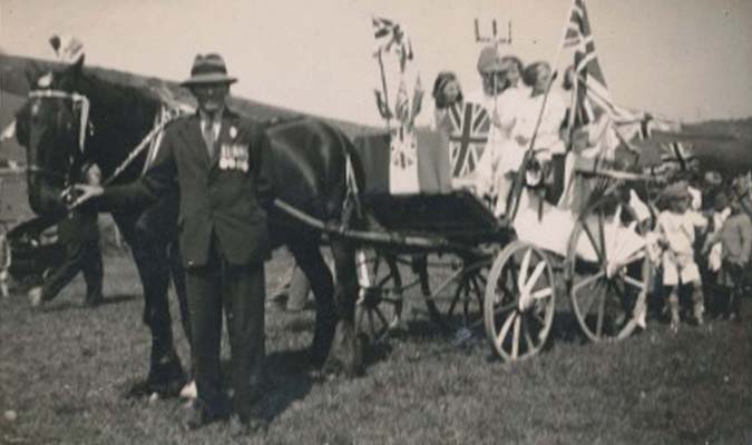 Arthur Munday holding head of horse pulling Queens' float